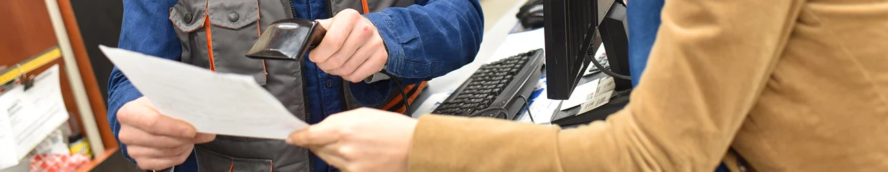 person at a cash register scanning a piece of paper