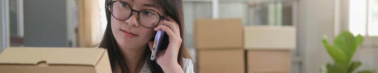 woman holding package talking to customer support on phone