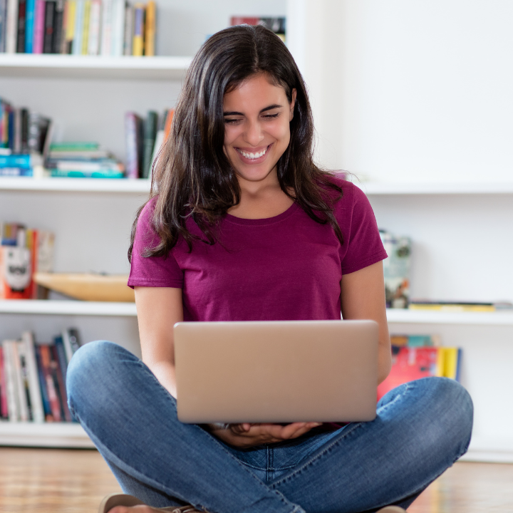 Woman sitting on floor smiling at computer