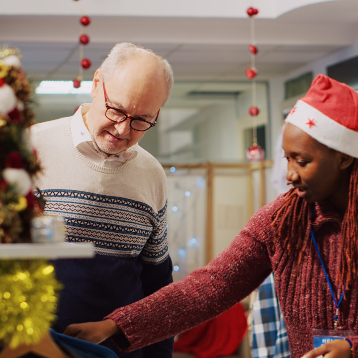 Man with woman wearing Santa hat looking at clothing