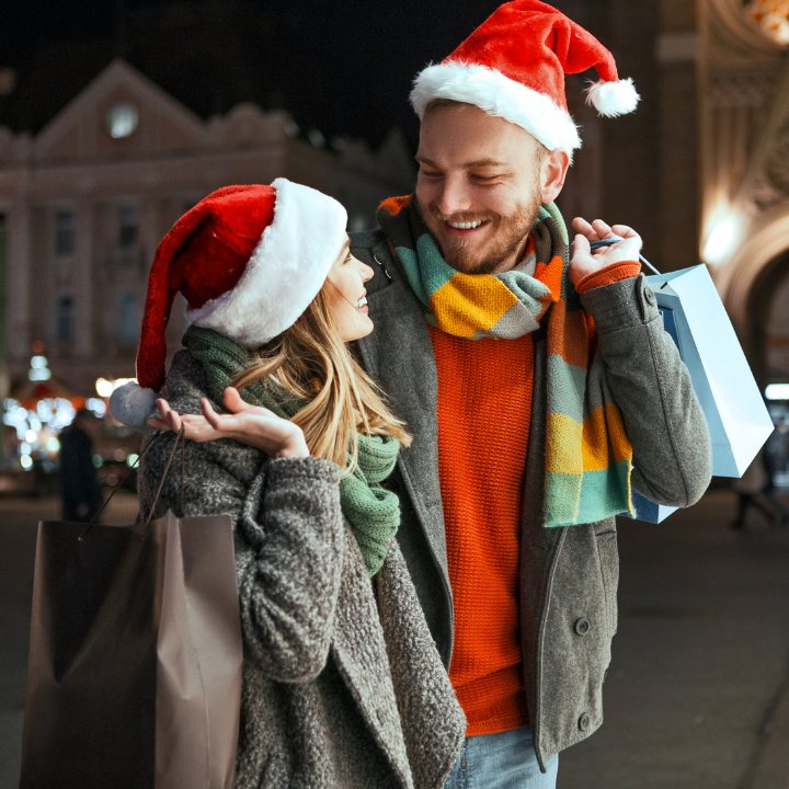 Two people holiday shopping embracing and smiling at each other