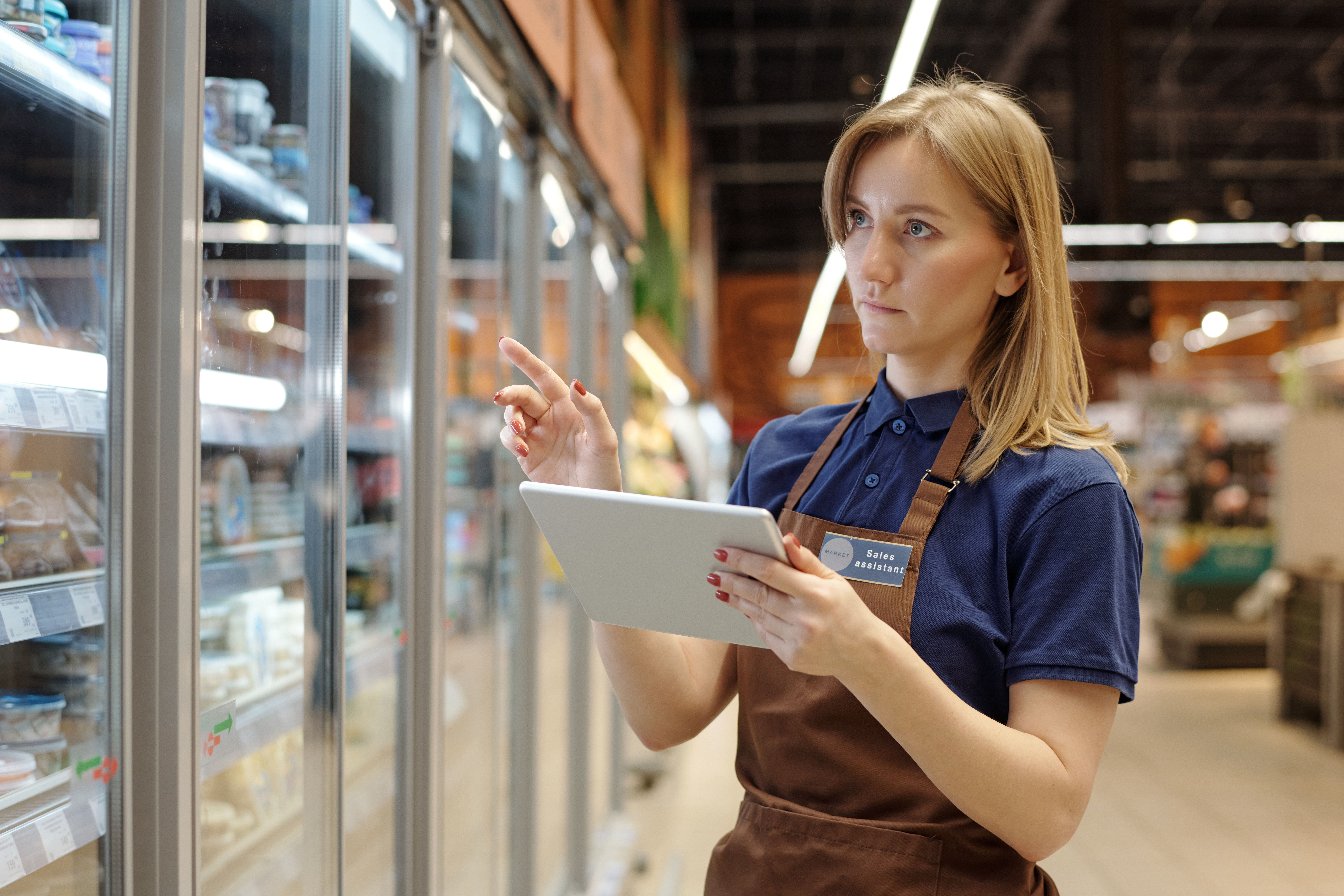 Woman looking at tablet in store to explore the impact of total retail loss on the business and find solutions to mitigate its effects. Get total retail loss examples and recommendations in this new playbook.