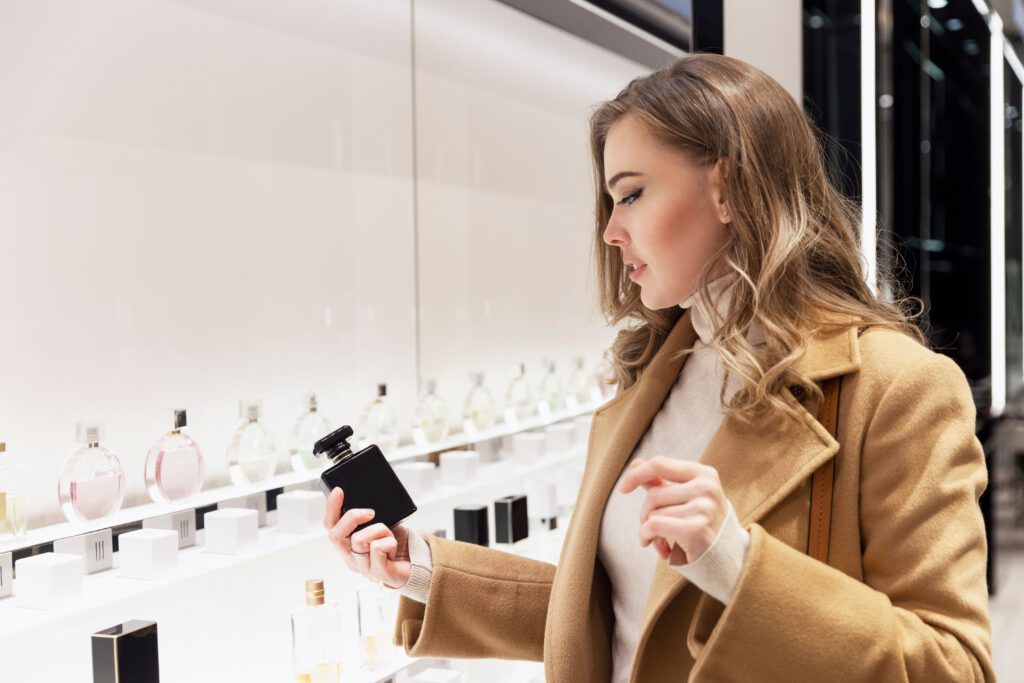 Young woman chooses perfume in luxury retail store.