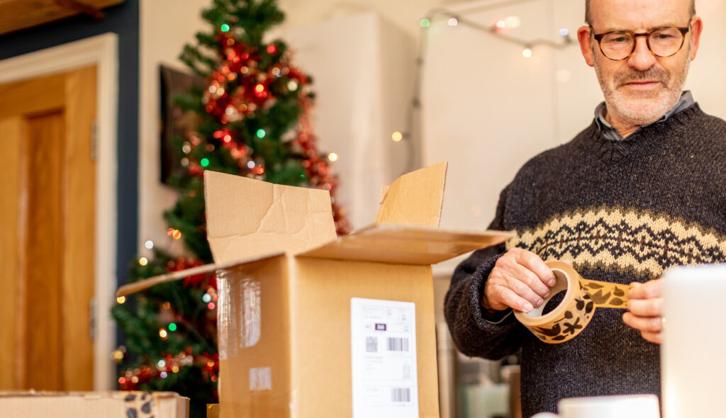 Man taping up box to return items to store. Retailers should understand holiday return abuse and implement measures to safeguard against retail fraud.